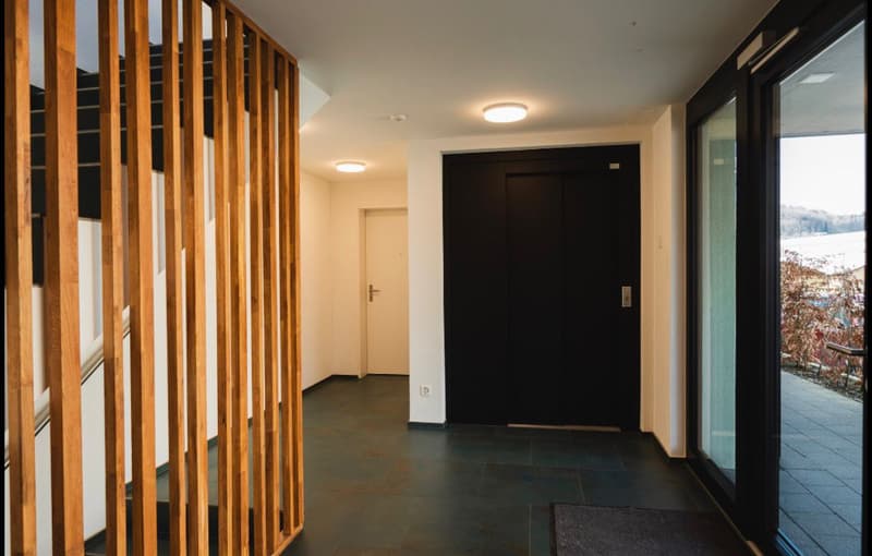 wooden railing, black door, white walls, tiled floor, glass door, light fixtures