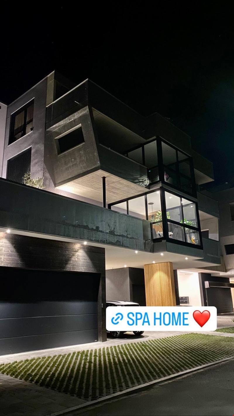 modern architecture, black exterior, glass walls and balcony, garage with black door, grassed area in front