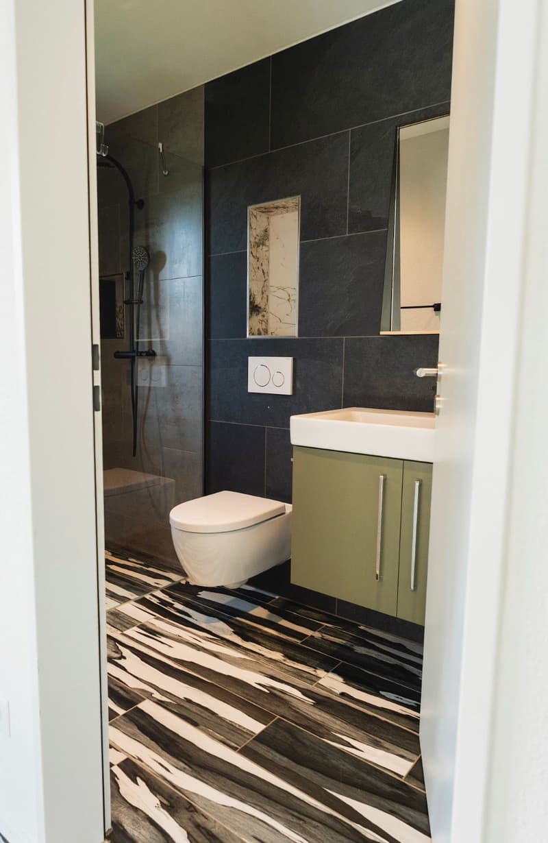 modern bathroom with black and white tiles, white toilet, white sink, mirror, shower