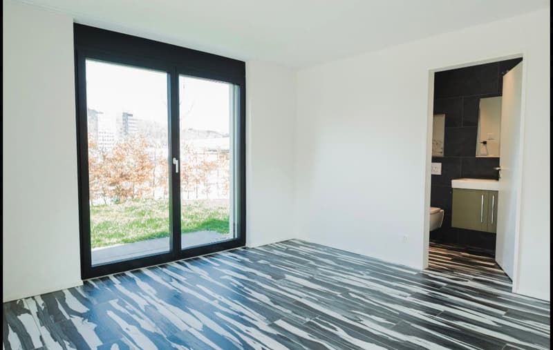 empty room, large sliding glass door, white walls, black and white flooring, open door to bathroom
