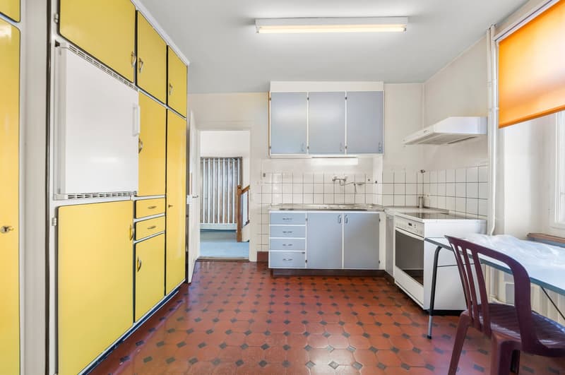 modern kitchen, yellow cabinets, white appliances, white countertops, tiled backsplash, stainless steel faucet, red tiled floor
