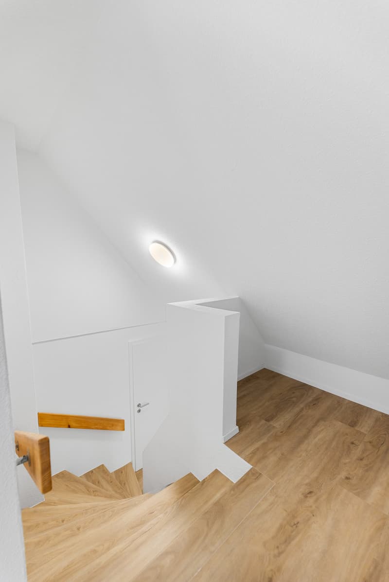 white walls, wooden floor, white ceiling, wooden handrail, white door, ceiling light