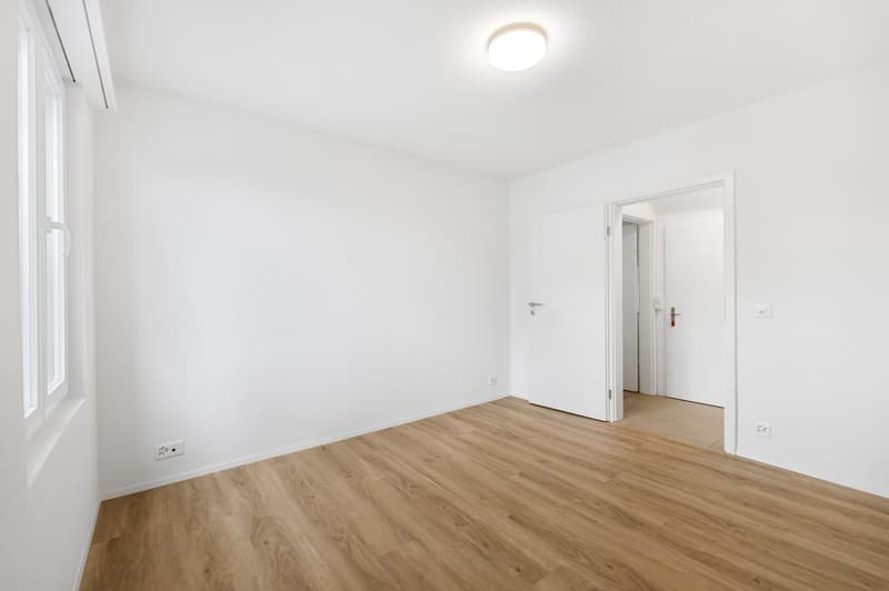 empty room, white walls, wooden floor, white doors, window, power outlets