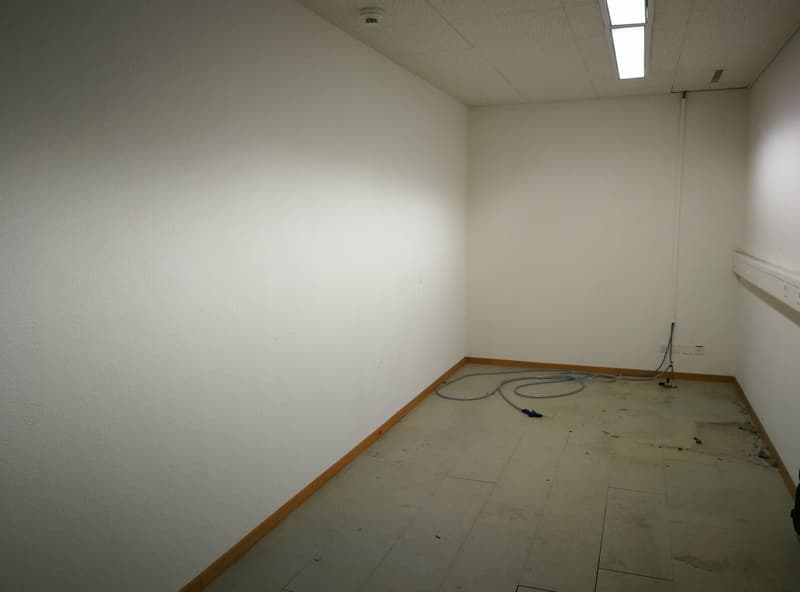 Empty room with white walls, concrete floor, and a light fixture on the ceiling.