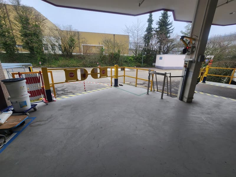 Empty parking area with barriers and a trash bin