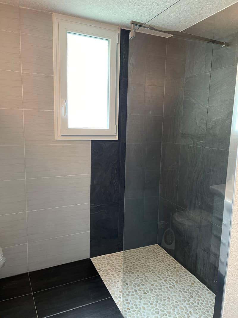 shower room with glass wall, window, black and white tiles