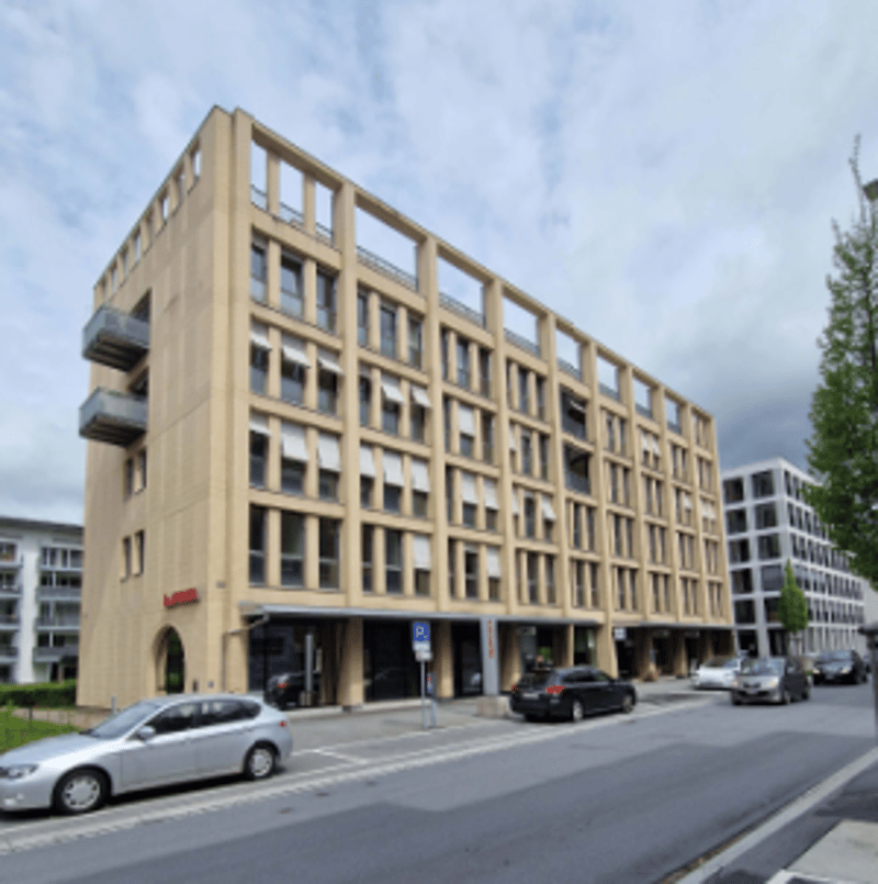 multi-story building, beige facade, multiple windows, cars parked in front