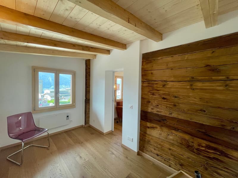 Empty room with wooden wall, wooden beams on the ceiling, hardwood floors, window with mountains view, wooden chair