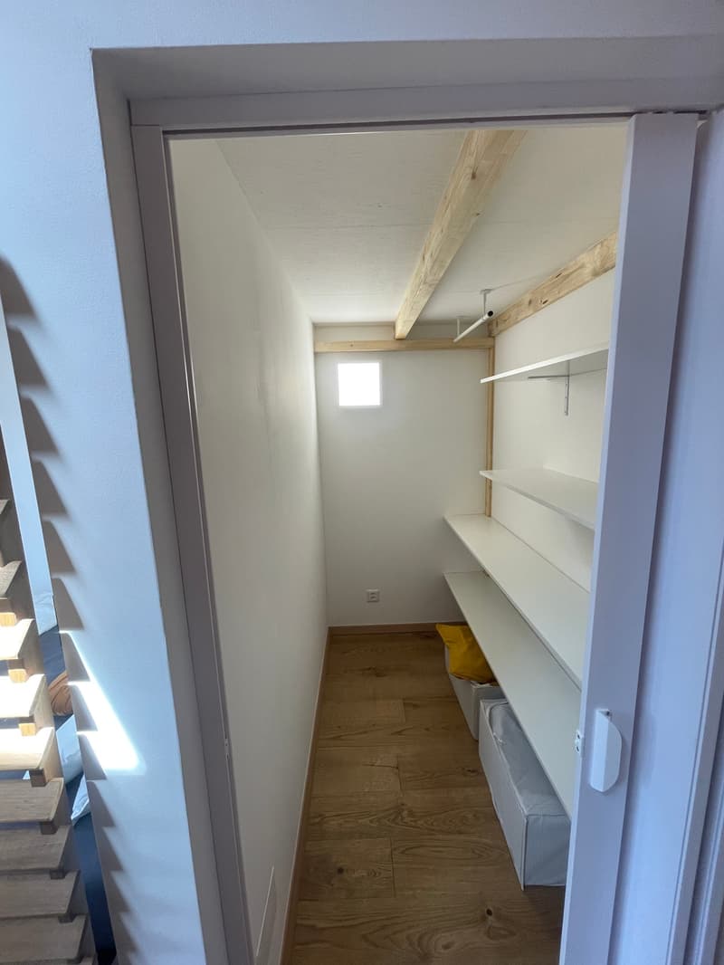empty storage room, wooden floors, white walls, white shelves, two white storage boxes, yellow bag