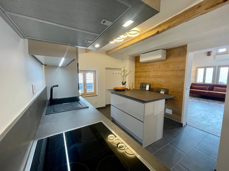 Kitchen with modern appliances, wooden wall, tile flooring, central island, sink, stove, window, vase with flowers