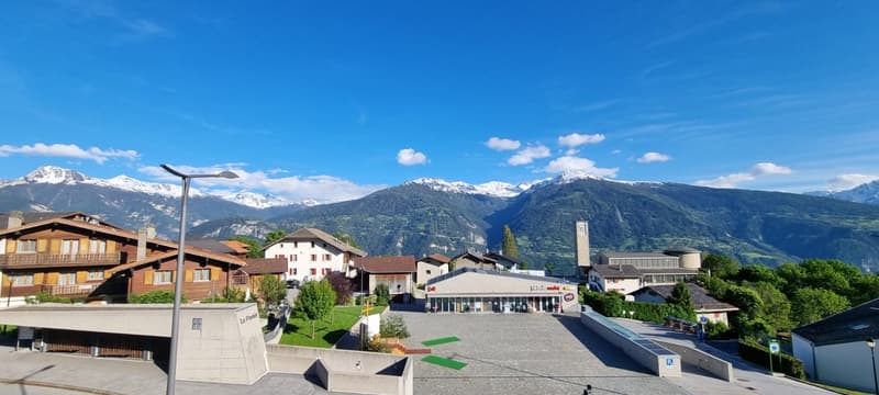 Small town with wooden buildings, mountains in the background, wide open area