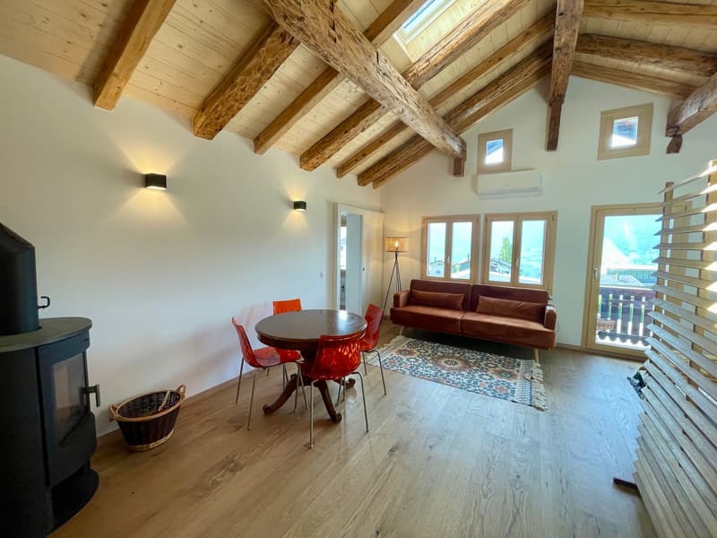 fireplace, round table with red chairs, wooden beams ceiling, brown sofa, carpet, windows, black wood burning stove