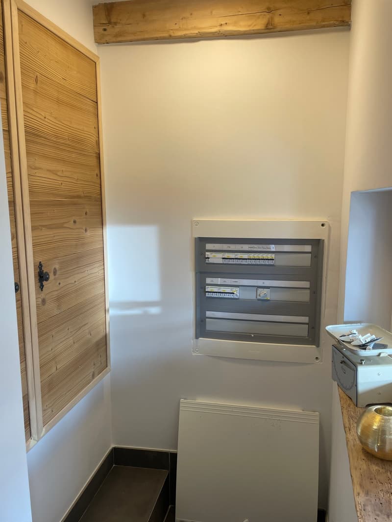 wooden door, electrical box mounted on wall, white wall, wooden shelf with decorative bowl