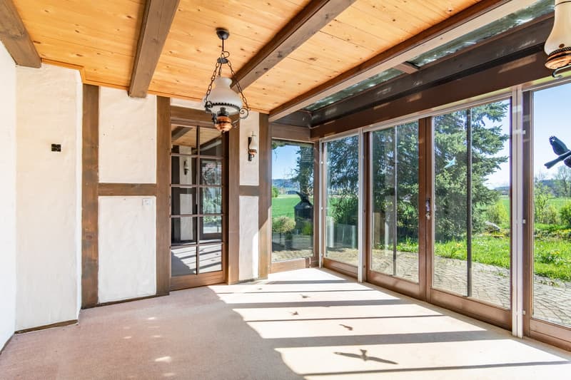 large glass doors, wooden ceiling, carpeted floor, chandelier, wall lamp