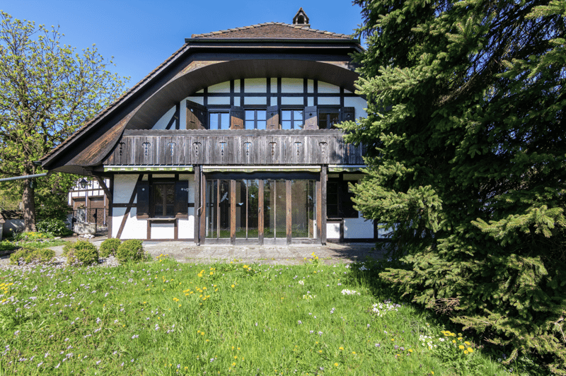 2 story house, brown roof, white walls, wooden balcony, glass doors, large windows, garden