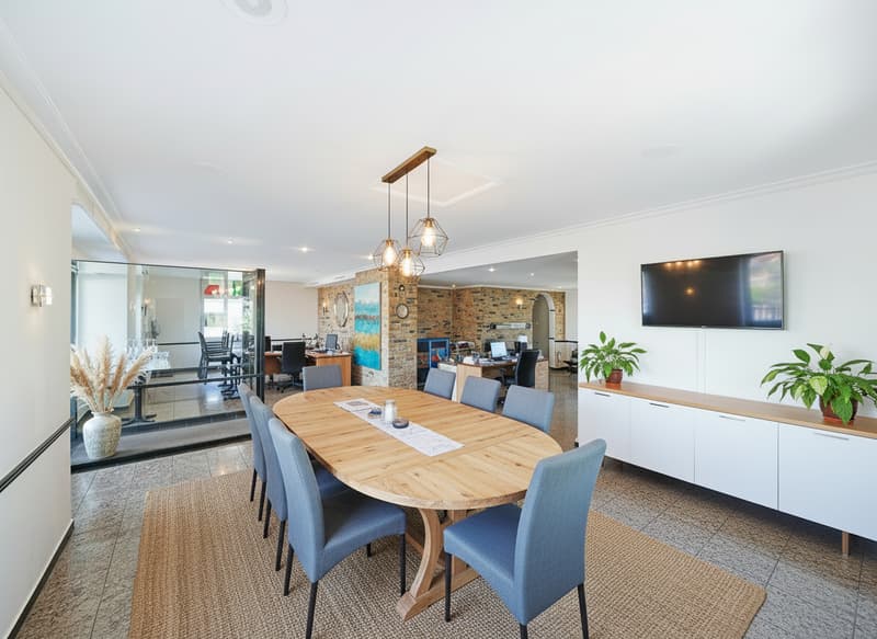 dining table, blue chairs, plants, office chairs, computer screens, office desk, rug, glass partition, large TV on the wall