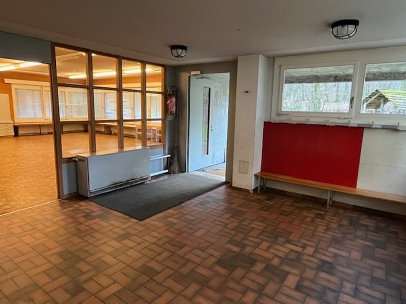 Wide open room with hardwood floors, large windows, a bench, and a door.