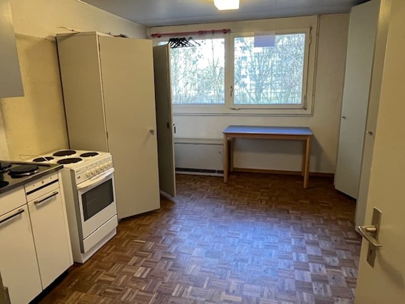 Kitchen: wooden floor, white appliances, table, window, metal coat rack