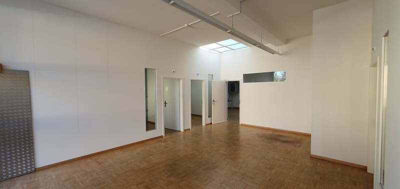 Empty room with wooden floor, white walls, glass doors, and a skylight