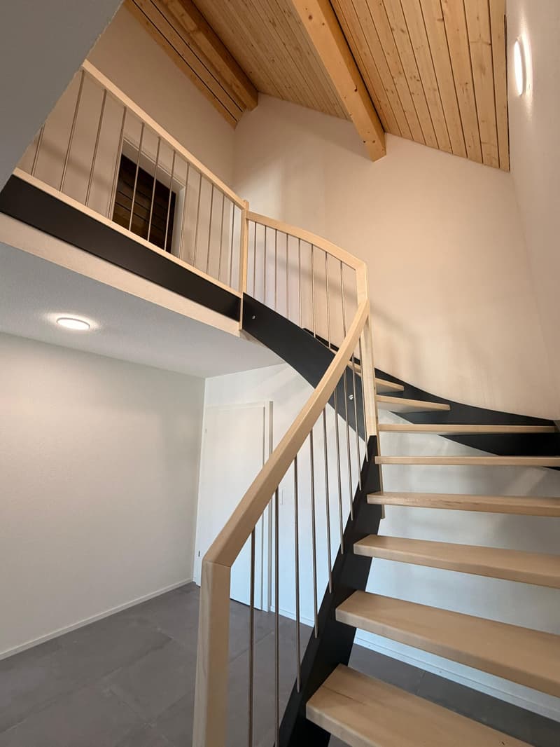 spiral staircase, wooden handrail, grey tile floor, white wall