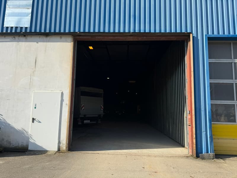 Industrial building, blue steel walls, concrete floor, open entrance, truck visible inside