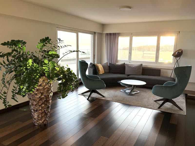 living room with hardwood floors, large windows, couch, coffee table, chairs, floor lamp, large potted plant