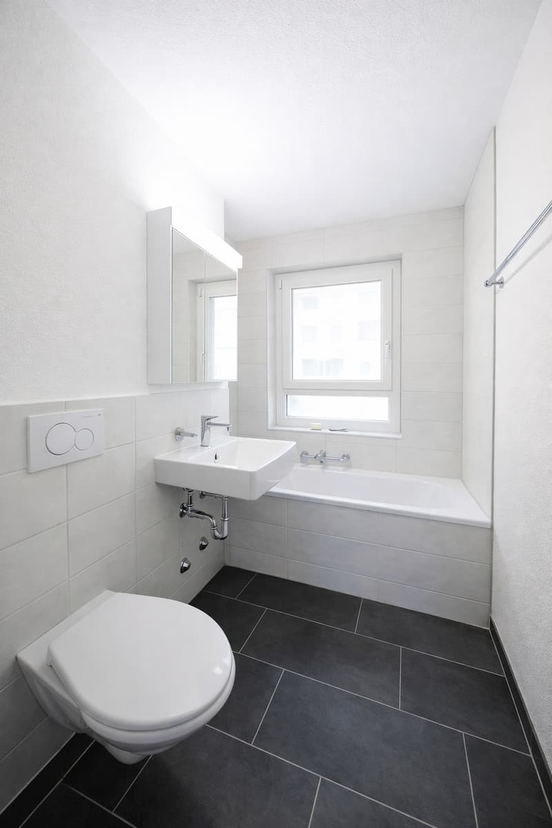 Bathroom: white tiles, white sink, white bathtub, white toilet, mirror, window