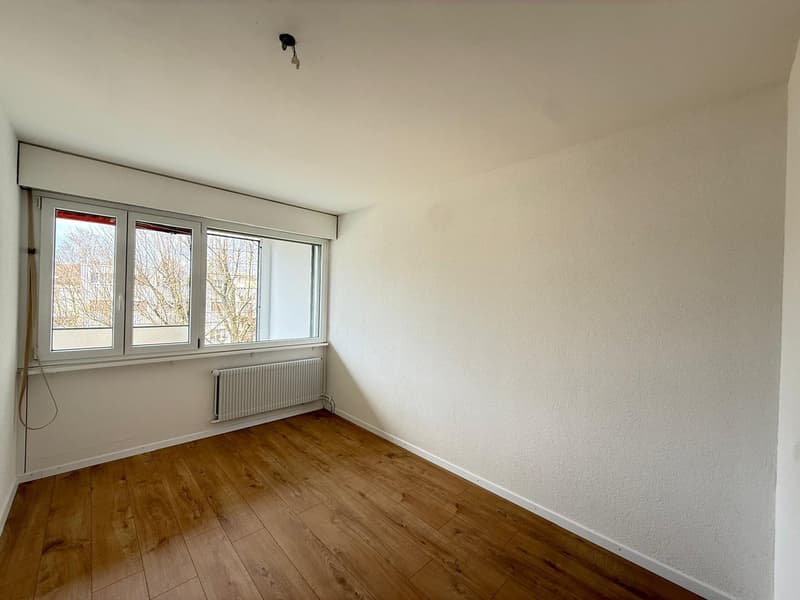 empty room, wooden floor, white walls, large window, white radiator