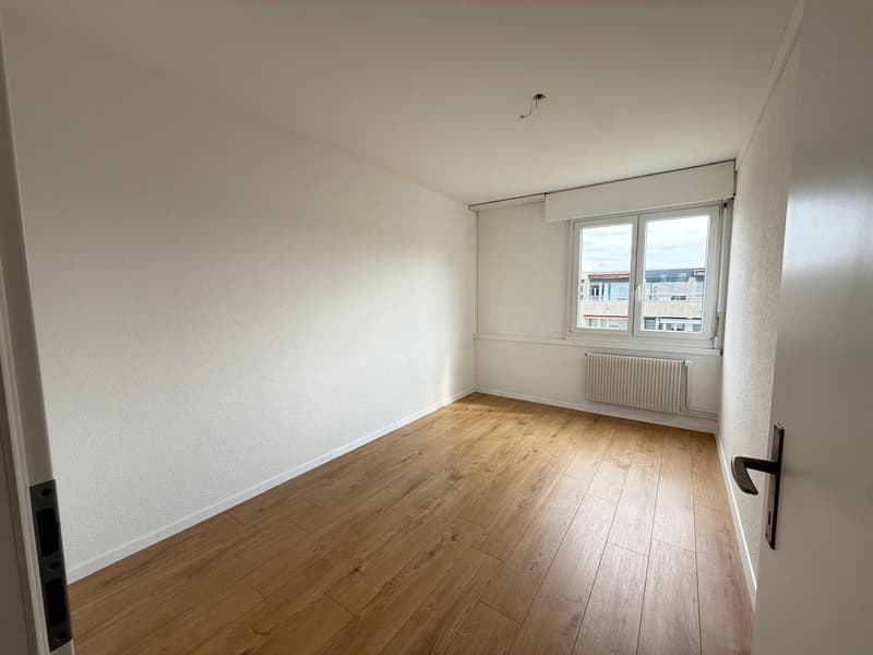 empty room, wooden floor, white walls, window with white radiator, door