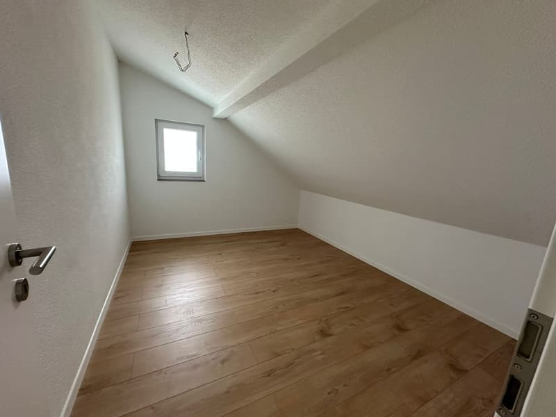 empty room, wooden floor, white walls, small window, slanted ceiling