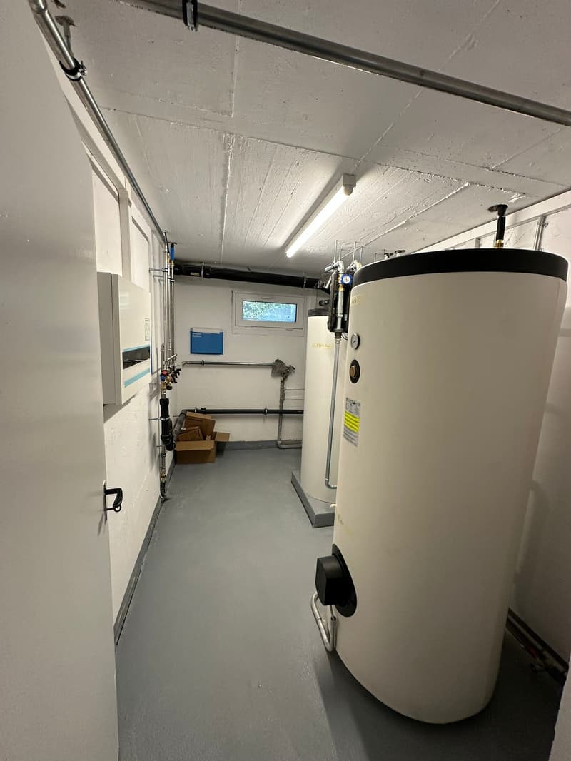 Utility room with water tanks, pipes, and a small window