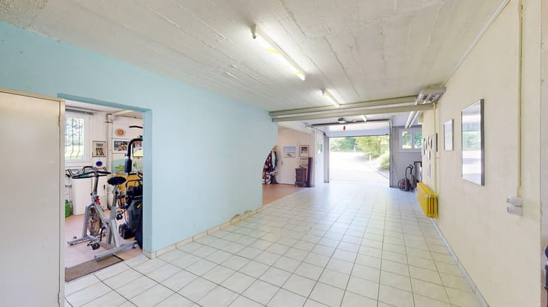hallway with tiles, bicycle, dumbbells, open garage with cars
