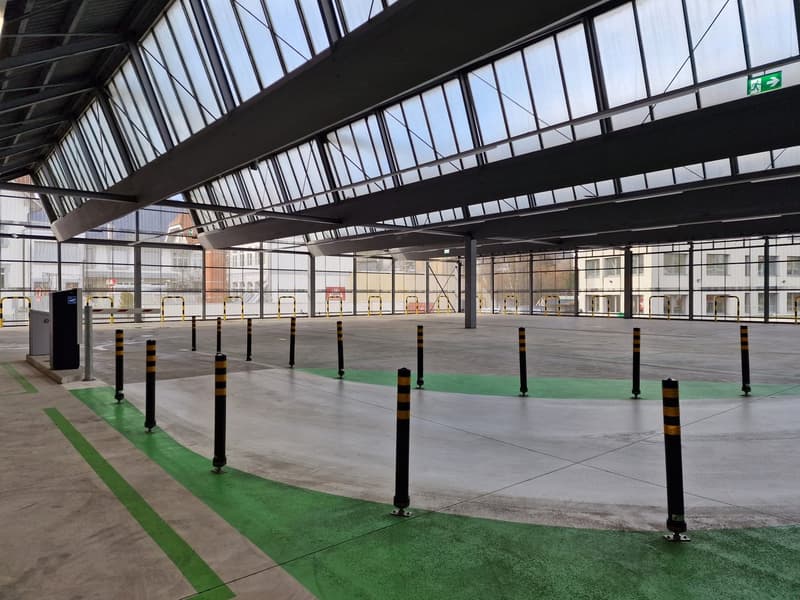 empty parking space, metal poles, bollards, green markings, windows, ceiling beams