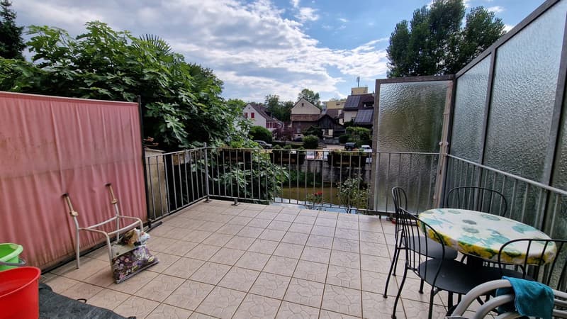 tiled floor, metal railing, table and chairs, green bucket, red bucket, pink wall, view of trees and houses