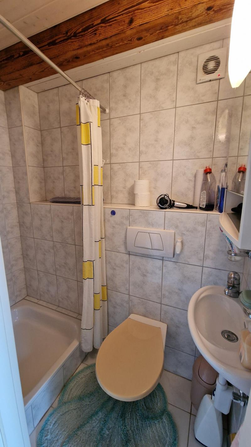small white bathroom with shower, bathtub, toilet, sink, shelves, and wooden ceiling