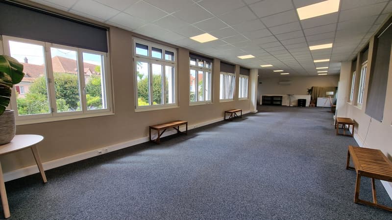 room with large windows, white carpet, wooden benches, small table, potted plant