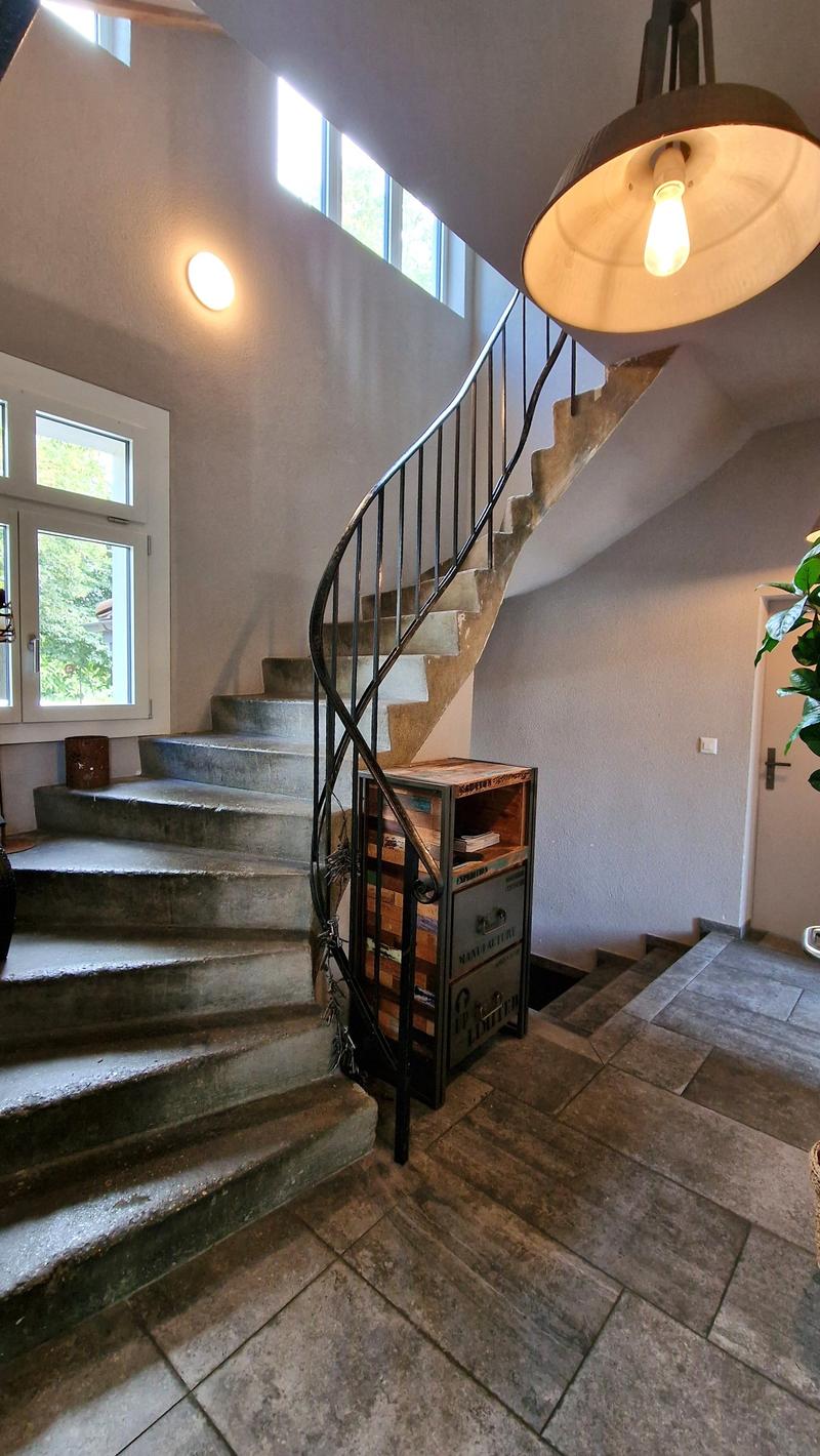 Wide staircase with wooden cabinets and metal railing, tiled entrance floor