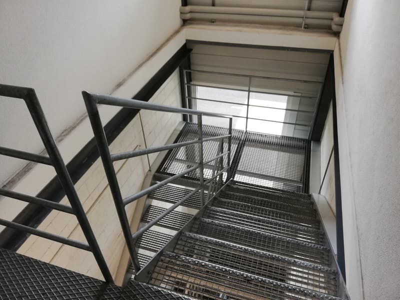 Metal staircase, mesh steps, handrails, light coming from the top