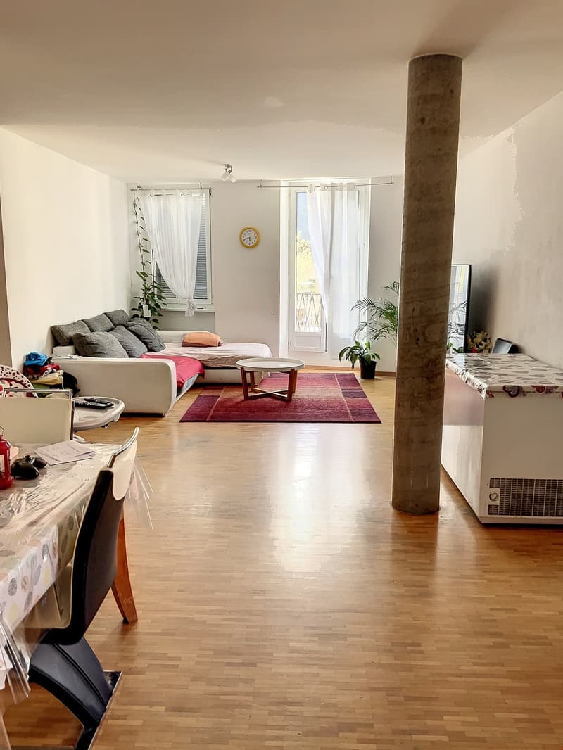 modern living room with hardwood floor, couch, table, rug, white walls, and windows