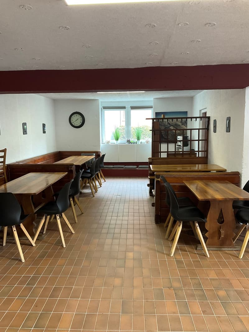 wooden dining tables, black chairs, wooden walls, tiled floor, clock, framed pictures, window with potted plants