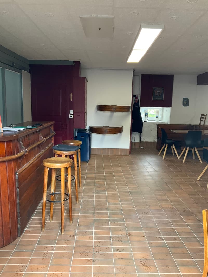 counter, 4 stools, wooden cabinets, blue trash bin, small window, chairs, table