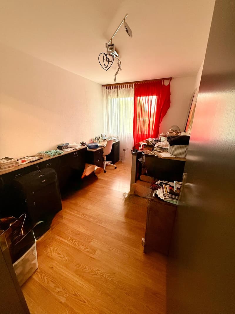 Office with desks and a chair, red curtains, and wooden floors