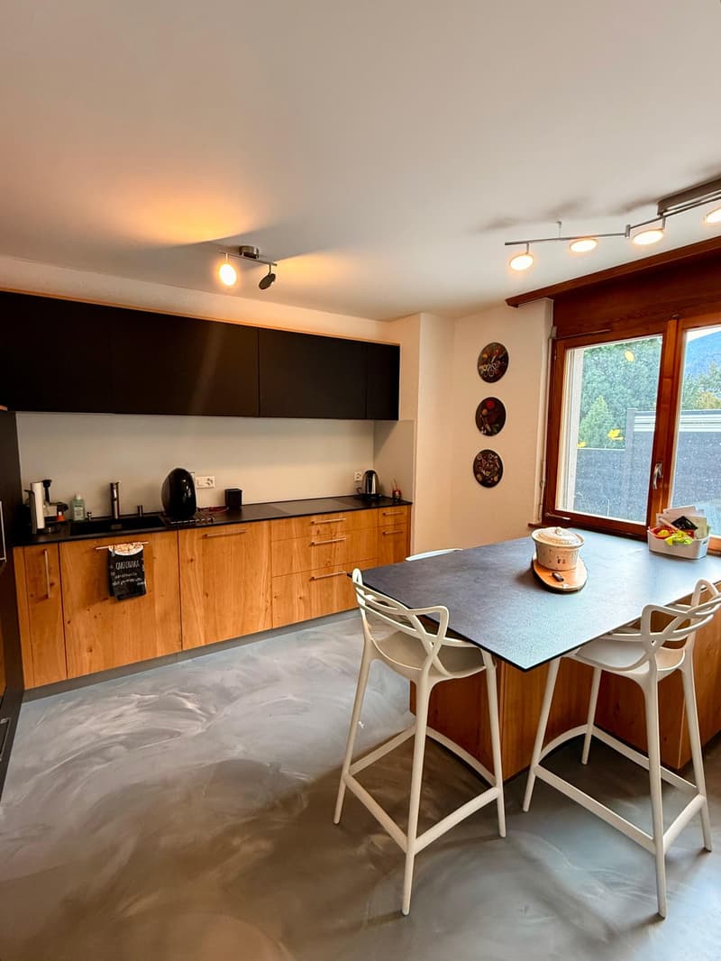 modern kitchen, wooden cabinets, granite countertop, large dining table, two bar stools, ceiling lamps, window with view