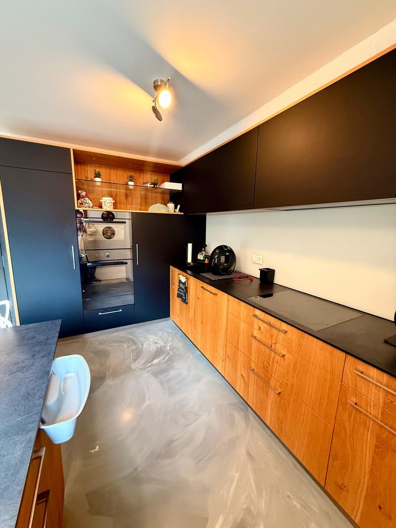 modern kitchen, wooden cabinets, black countertops, integrated oven, dishwasher, gray and black appliances