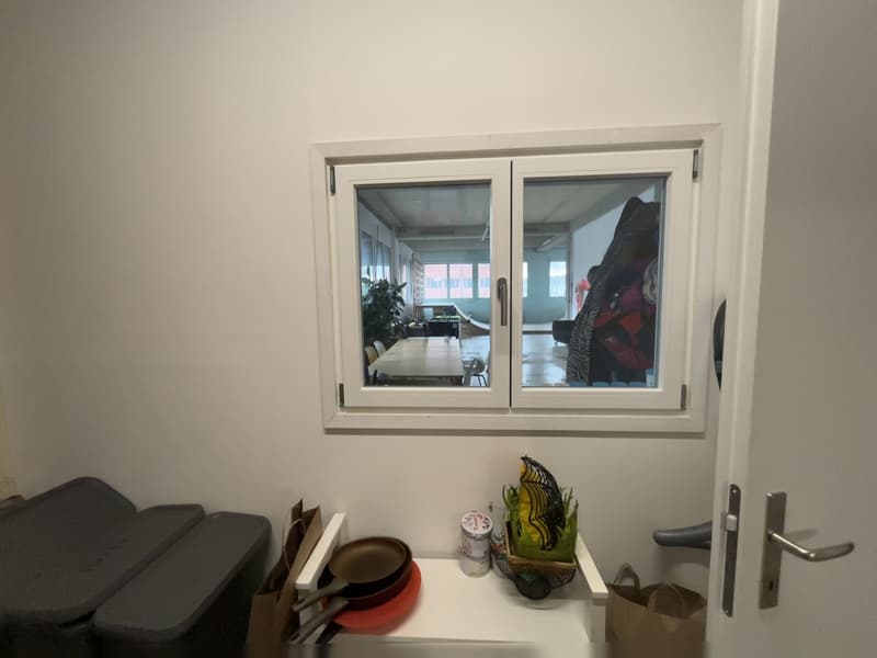 small room, small white shelf, tableware on the shelf, window overlooking a courtyard, door on the right