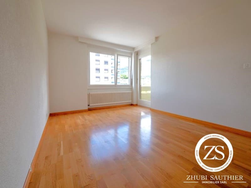 Empty room with wooden floors, white walls, windows, glass door, and radiator.