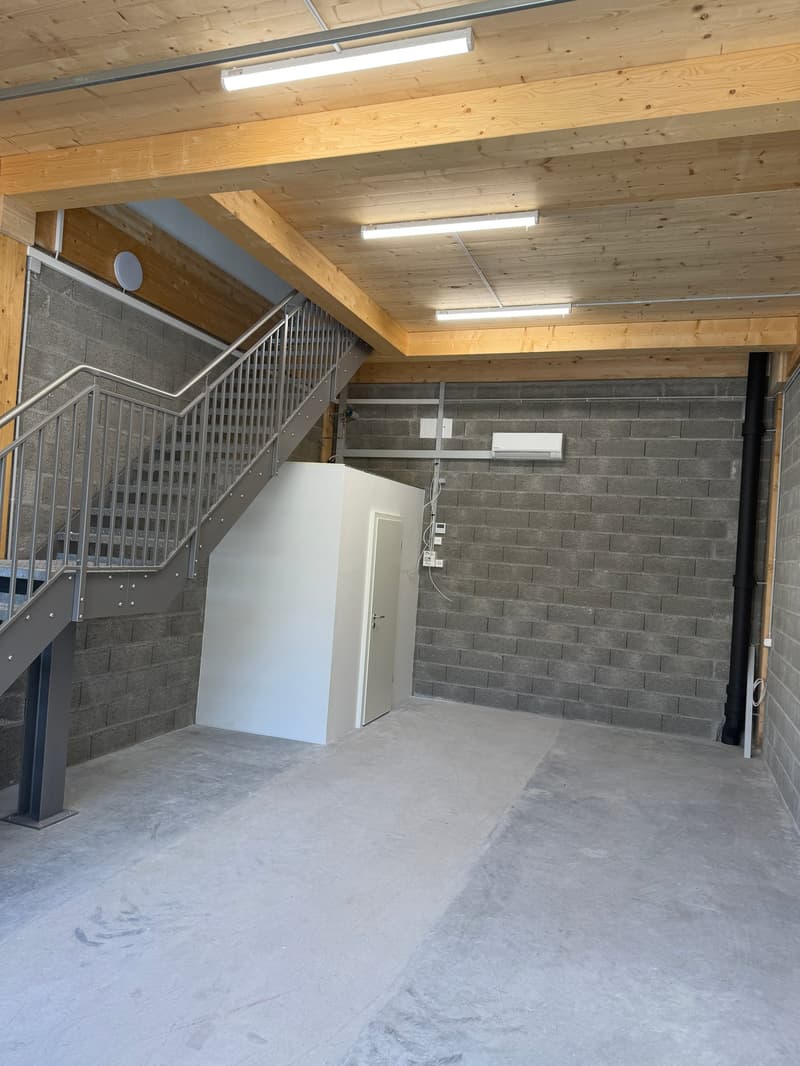 empty room, concrete floor, brick wall, metal staircase, white door, air conditioner