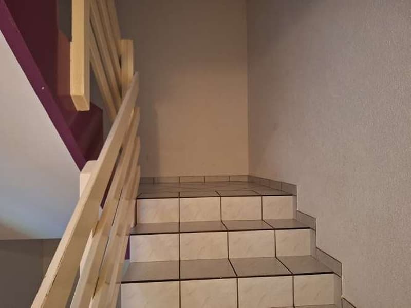 Raised ground floor with beige tile steps, wooden handrail, burgundy accent, cream wall