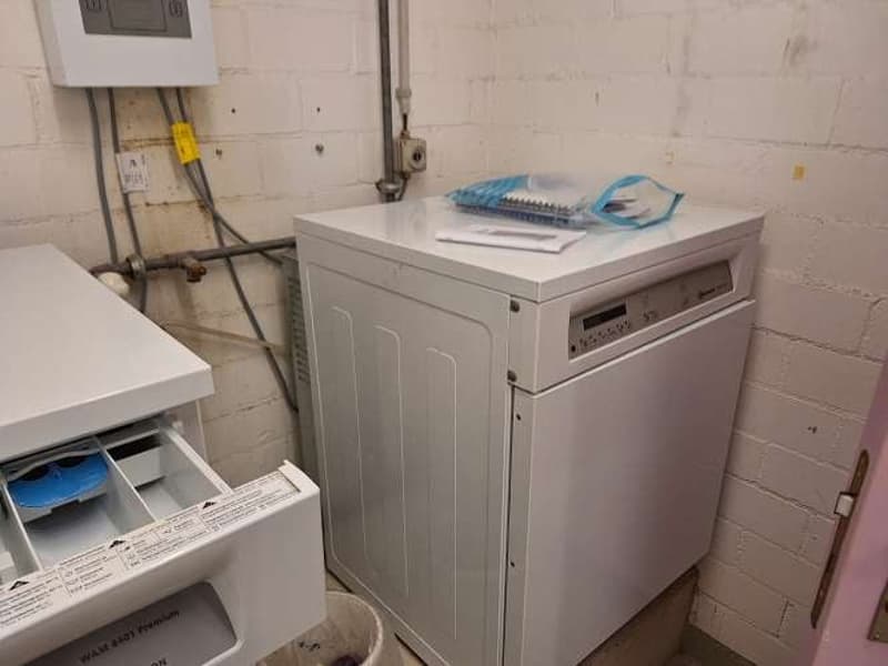Laundry room with washing machine and dishwasher against a brick wall
