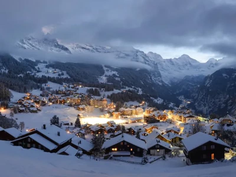 Swiss village, multiple chalets, covered in snow, illuminated by lights